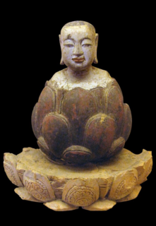 The boy Buddha rising up from a lotus. Crimson and gilded wood, Trần-Hồ dynasty, Vietnam, 14th-15th century